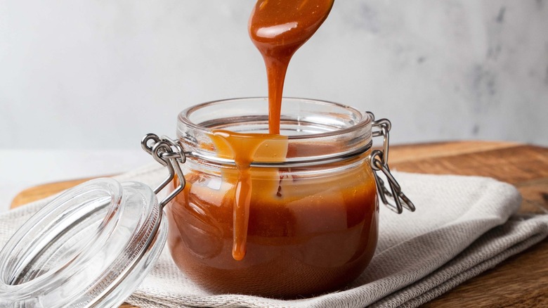 open caramel jar with spoon dripping inside