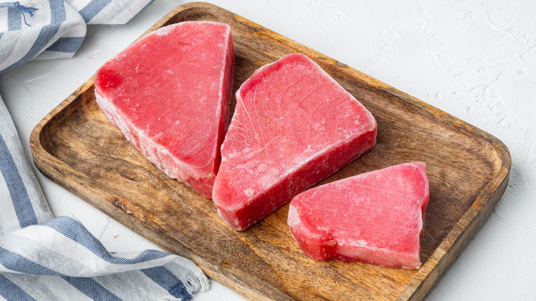 Frozen tuna steaks on cutting board