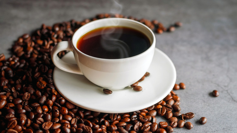 Cup of coffee on saucer with coffee beans