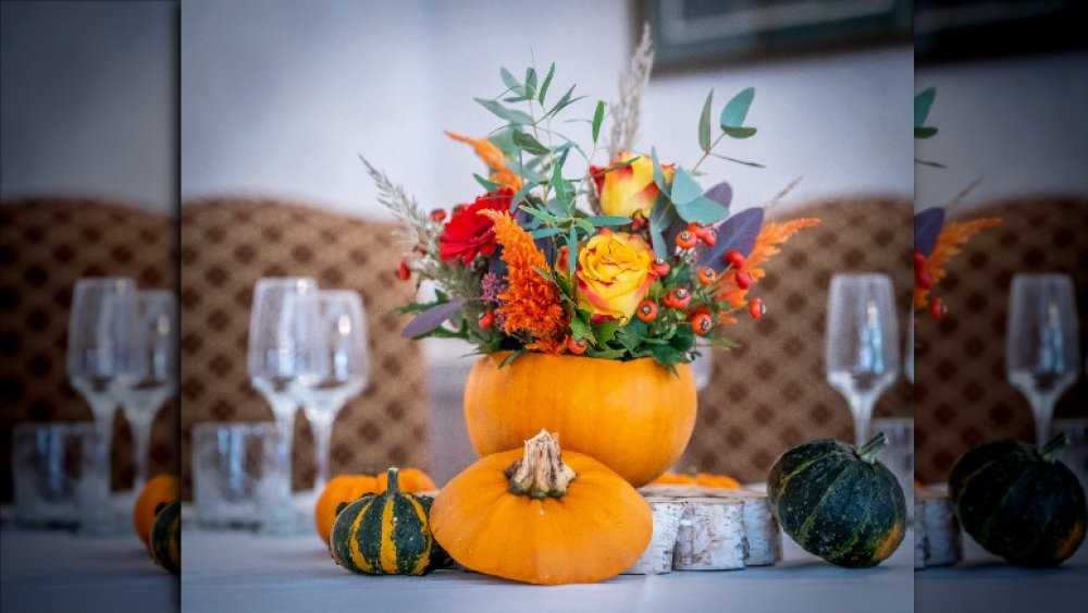 fall flowers inside a pumpkin on a dinner table