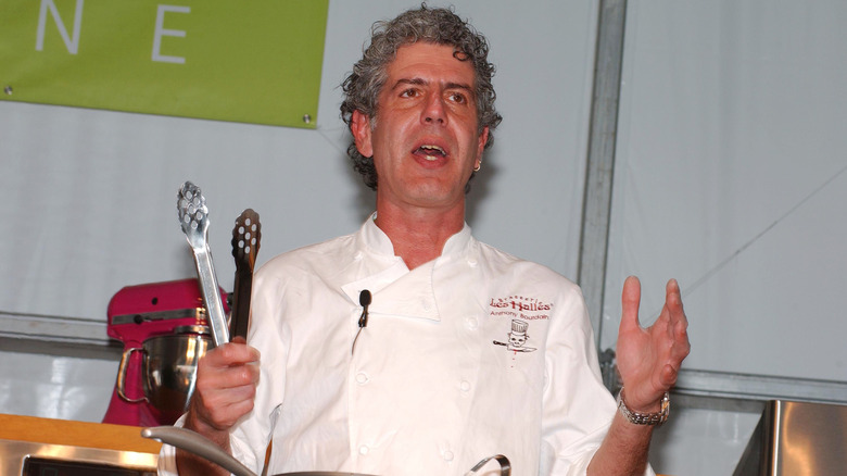 Anthony Bourdain holding tongs