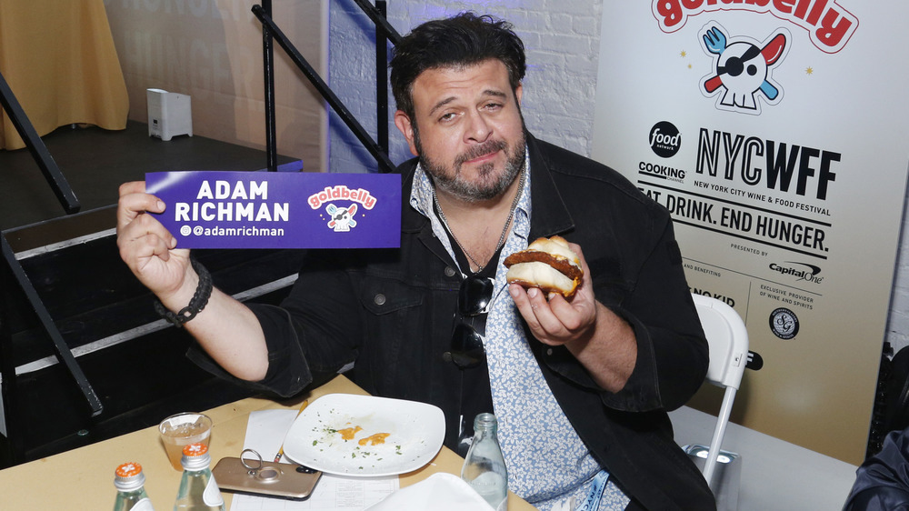 Adam Richman holding a burger