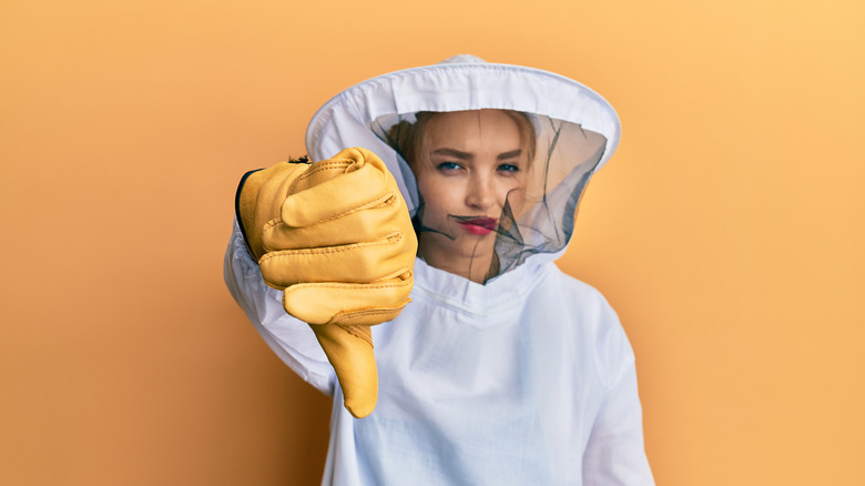 Woman in a beekeeper uniform thumbs down