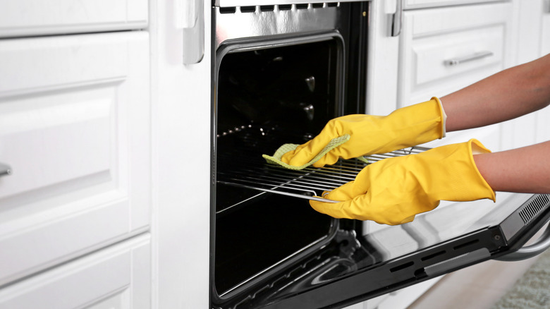 Gloved hands cleaning oven