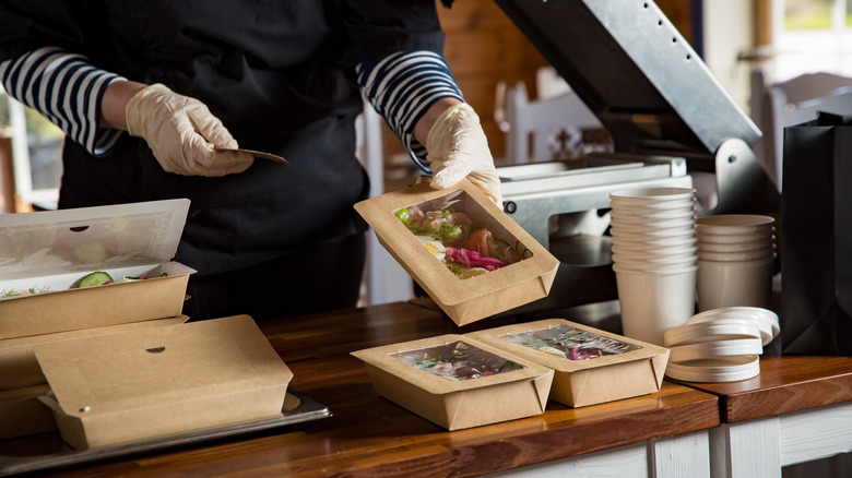 Food delivery orders prepared by worker wearing gloves