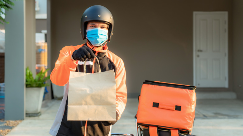 Food delivery guy with mask on holding a bag