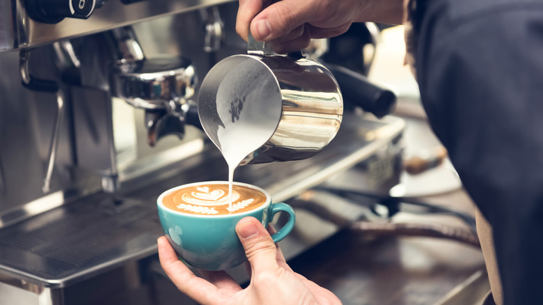 Person making a latte in a blue cup