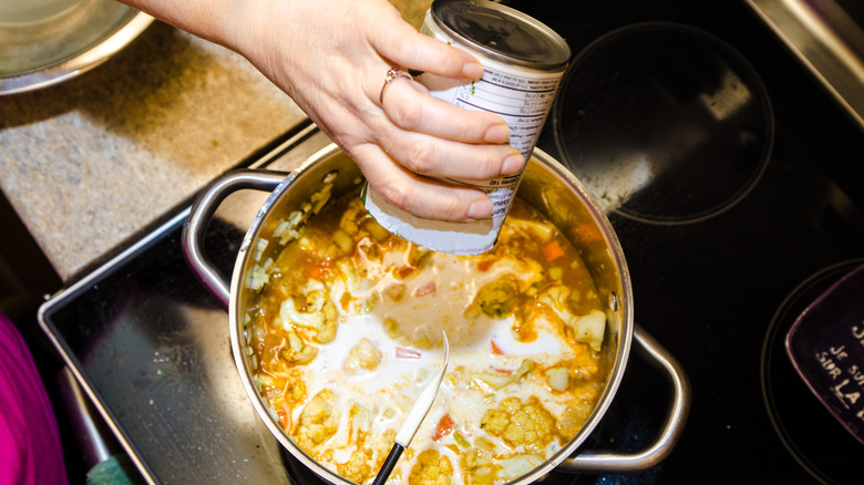 hand pouring liquid into pot