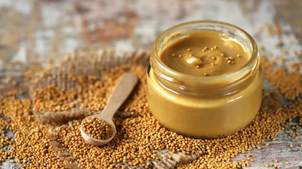 Jar of mustard with seeds and wooden spoon