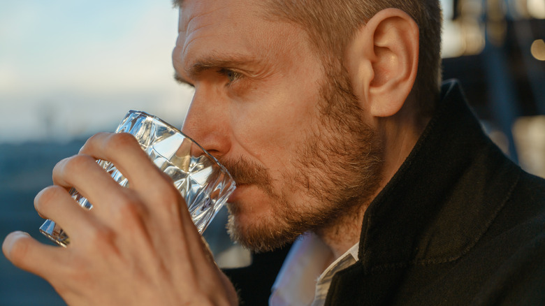 man sipping clear liquor