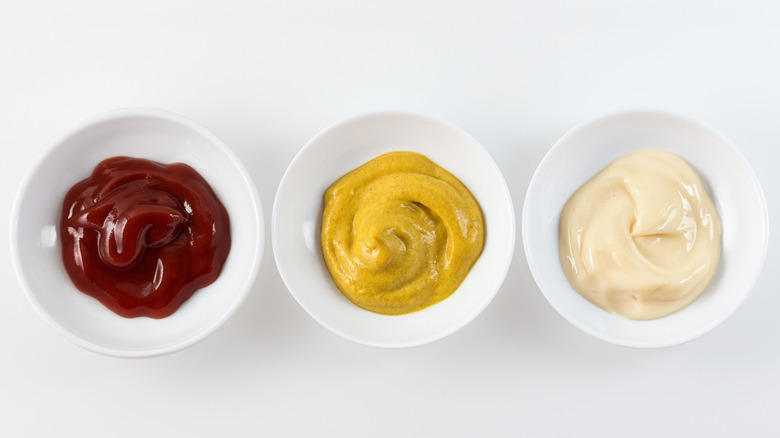 white bowls of ketchup, mustard, mayonnaise