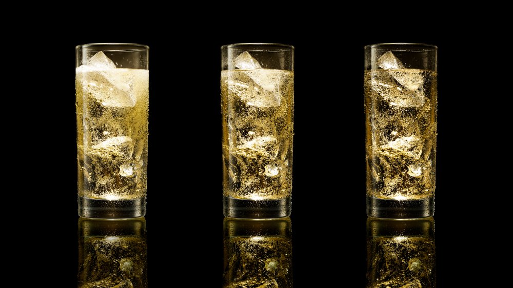 three glasses of ginger ale with ice on black background