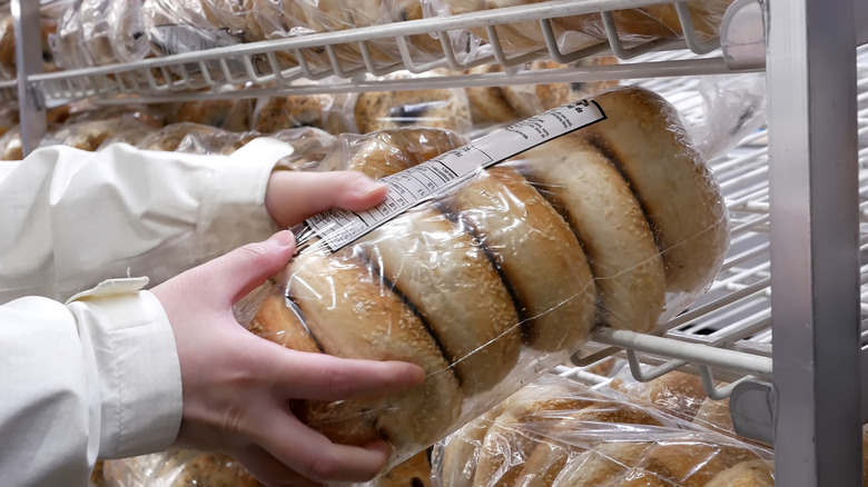 Person grabbing a sleeve of Costco bagels off the shelf.