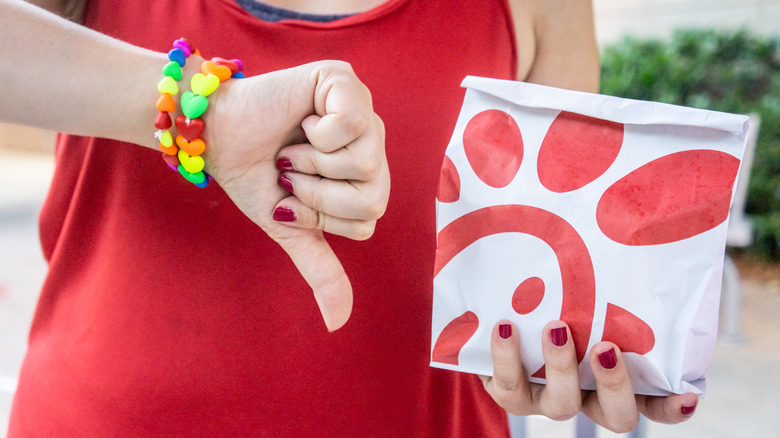 Someone giving a thumbs down to a Chick-fil-A bag