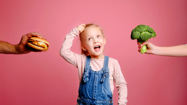 girl choosing between unhealthy and healthy food