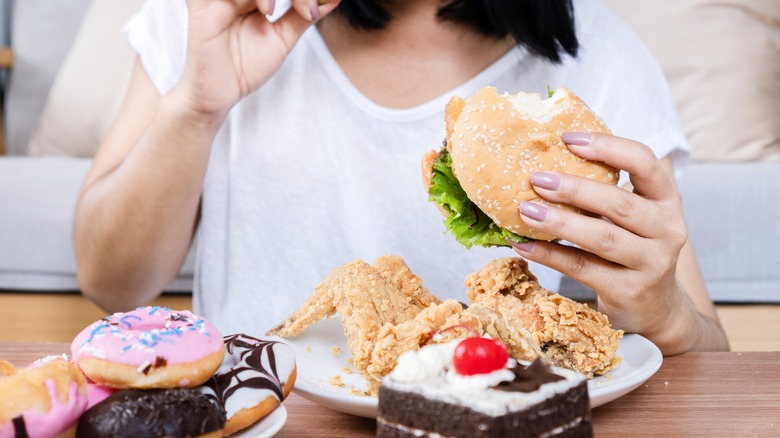 Woman at table covered with unhealthy food