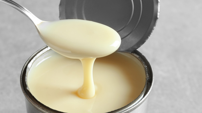 Condensed milk in a can with a spoon