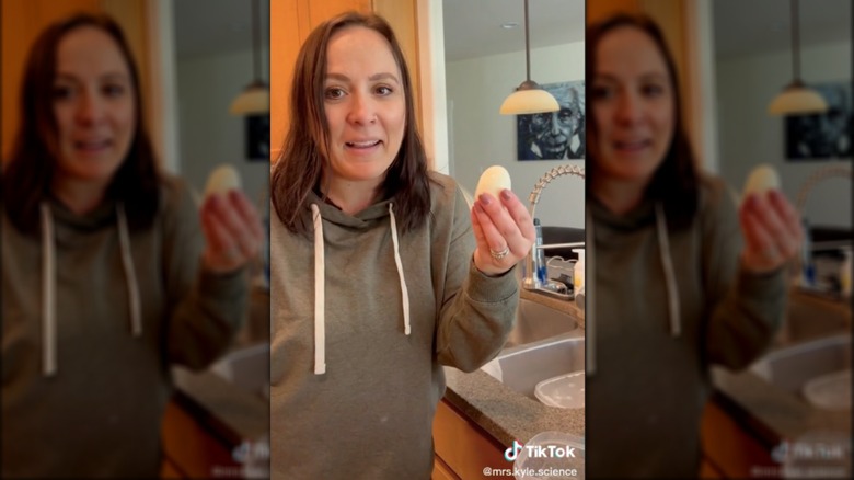 woman holding up hard-boiled egg in kitchen