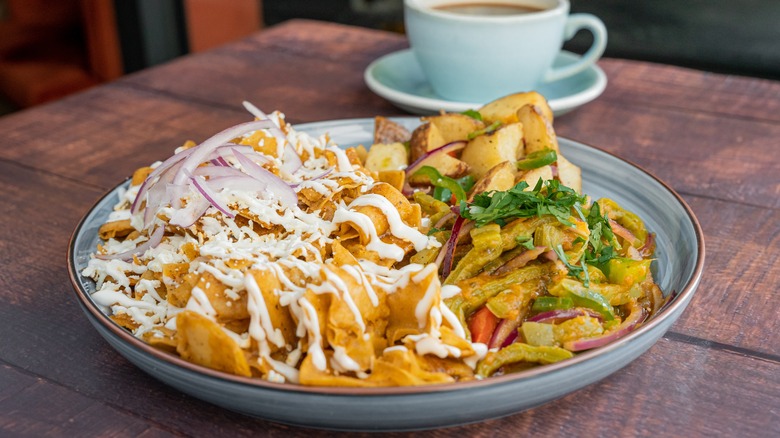 Plate of chilaquiles with coffee in background