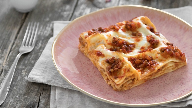 Lasagna Bologenese slice on a pink plate with fork