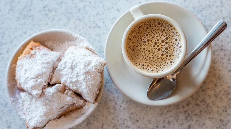 hot cup of coffee next to bowl of beignets