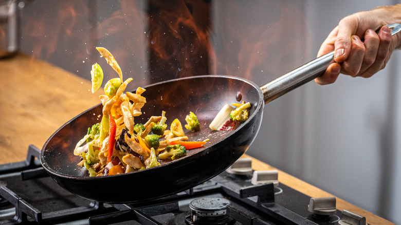 hand sautéing veggies in a wok 