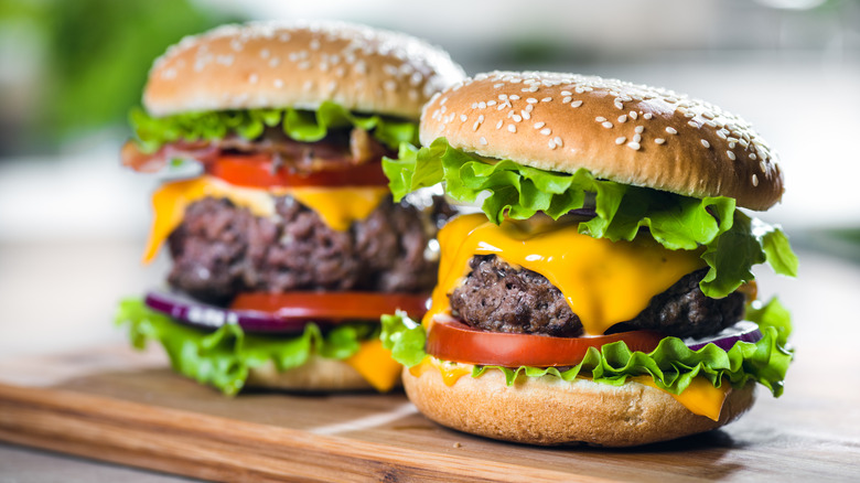 two homemade cheeseburgers with lettuce, tomato, onions, pickles, and a seeded bun