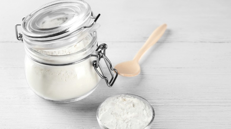 Jar of cornstarch with a spoon and small bowl filled with cornstarch