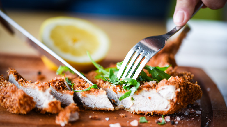 cutting into fried chicken