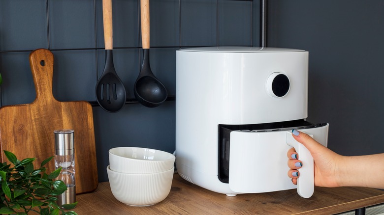 Hand pulling out air fryer