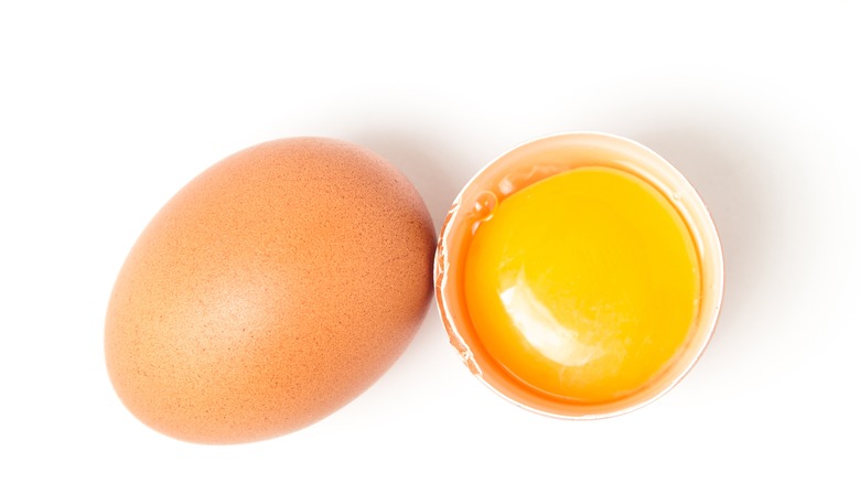 whole egg next to cracked egg and yolk