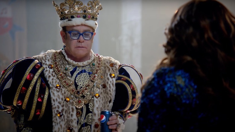 Elton John dressed as a king and holding Pepsi can