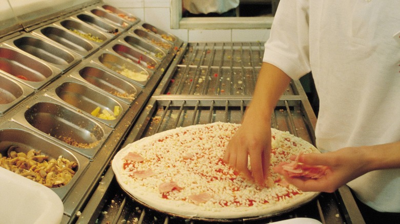 Telepizza employee putting toppings on pizza