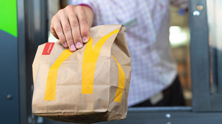 Hand holding a McDonald's bag out of window