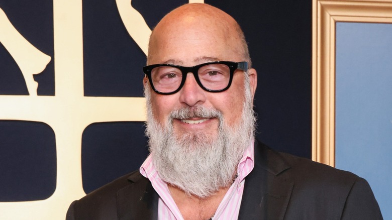 Andrew Zimmern wearing black rimmed glasses and smiling at the Daytime Emmy Awards