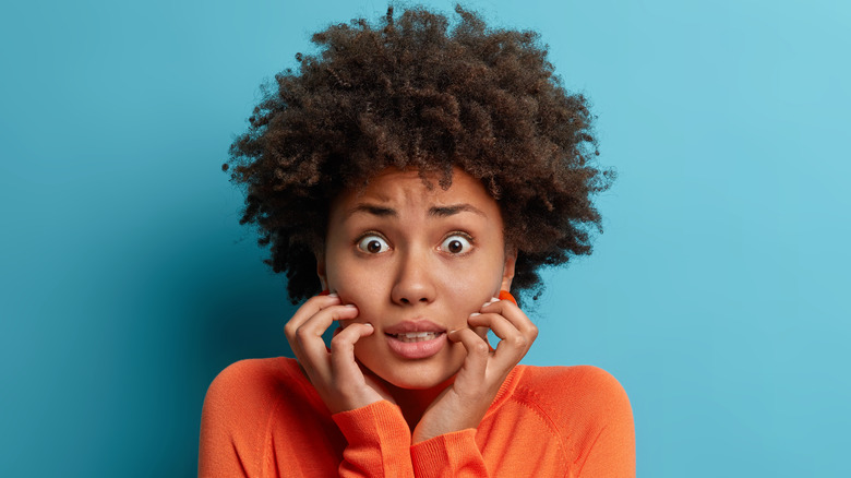 Frightened woman against turquoise background 