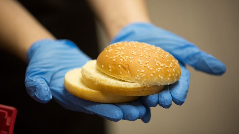 McDonald's employee holds sliced bun in gloved hands