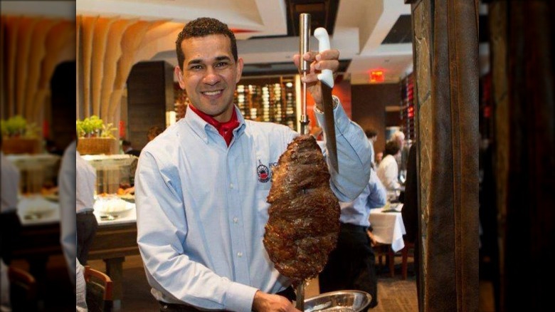 Fogo server holding skewer of meat