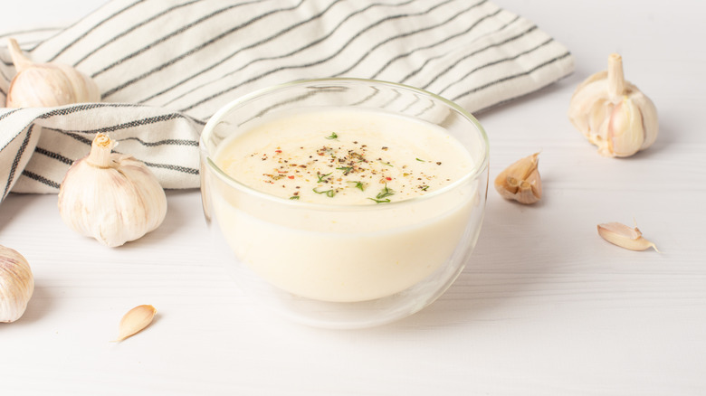 small bowl of aioli with garlic bulbs