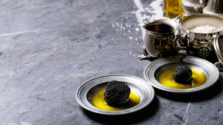 Black truffles in oil placed on silver plates