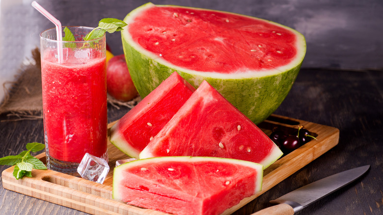 Watermelon on a cutting board with a glass of watermelon juice