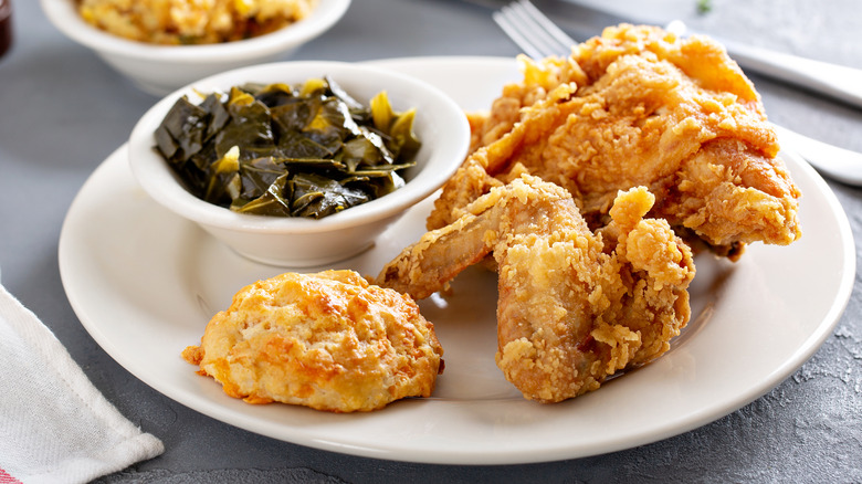 Plate of fried chicken with collard greens and biscuit