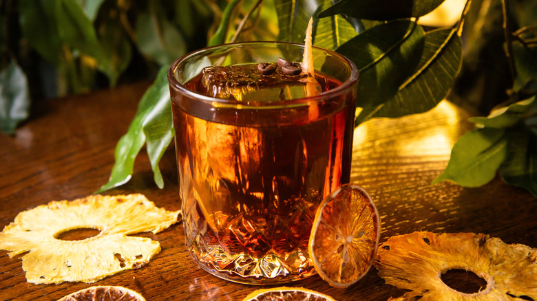 Whiskey based cocktail on table with foilage