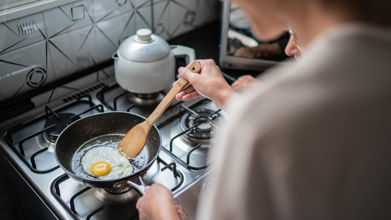 person frying egg in pan