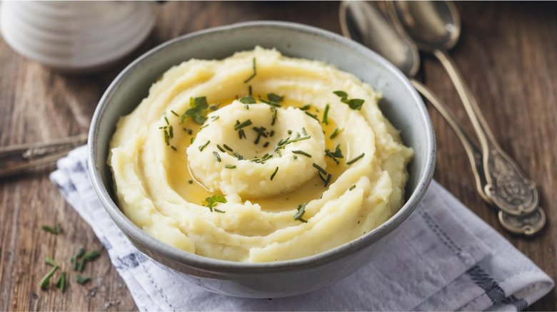 a bowl of fluffy and creamy mashed potatoes in a rustic setting