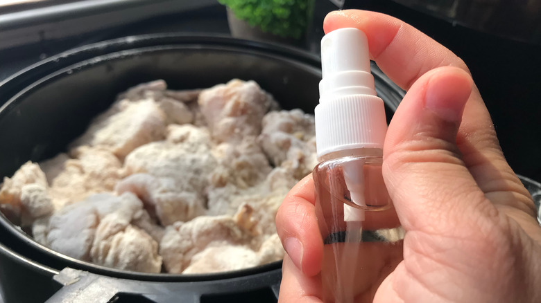 spritzer bottle with frozen chicken in air fryer