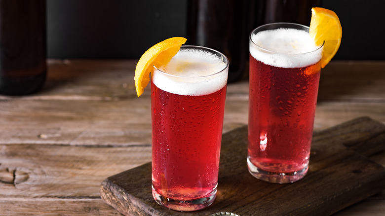 Two sour beers in glasses garnished with an orange slice