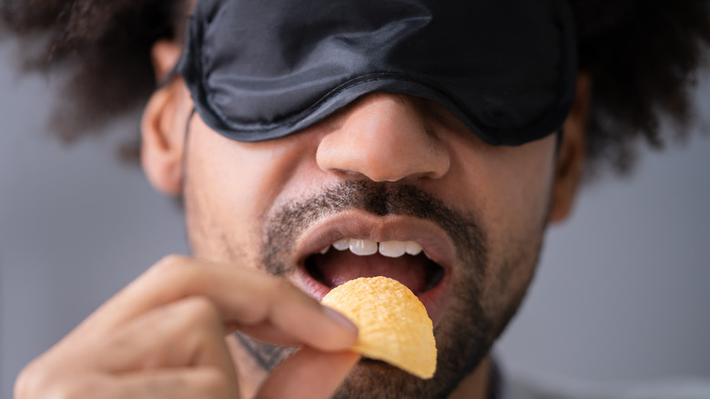 Blindfolded man eating potato chip