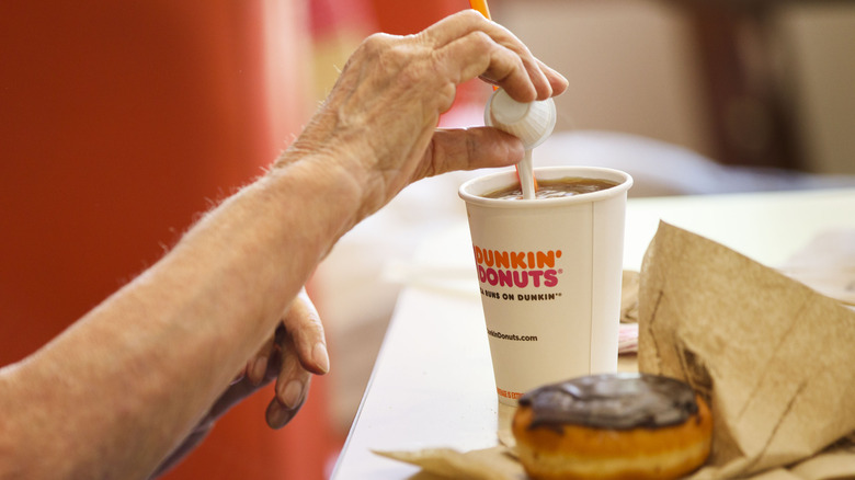 Pouring creamer into a Dunkin' coffee