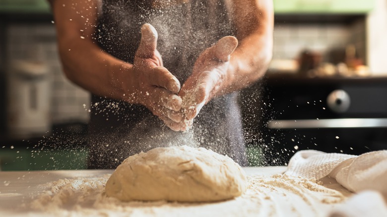 man making bread with a cloud of flour